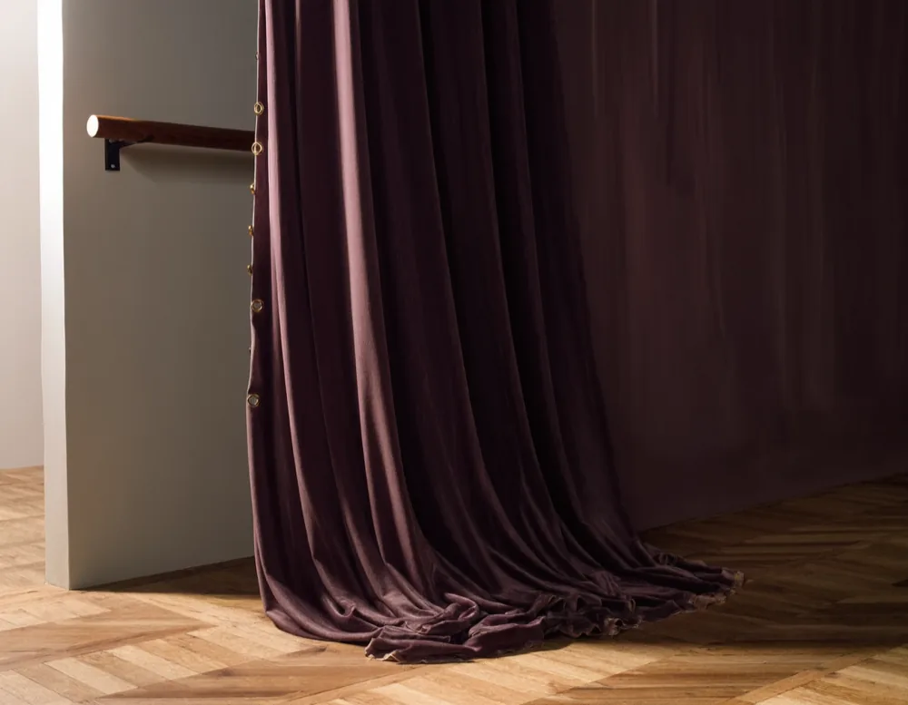 Deep aubergine velvet drapes falling onto herringbone parquet, lit from one side by daylight